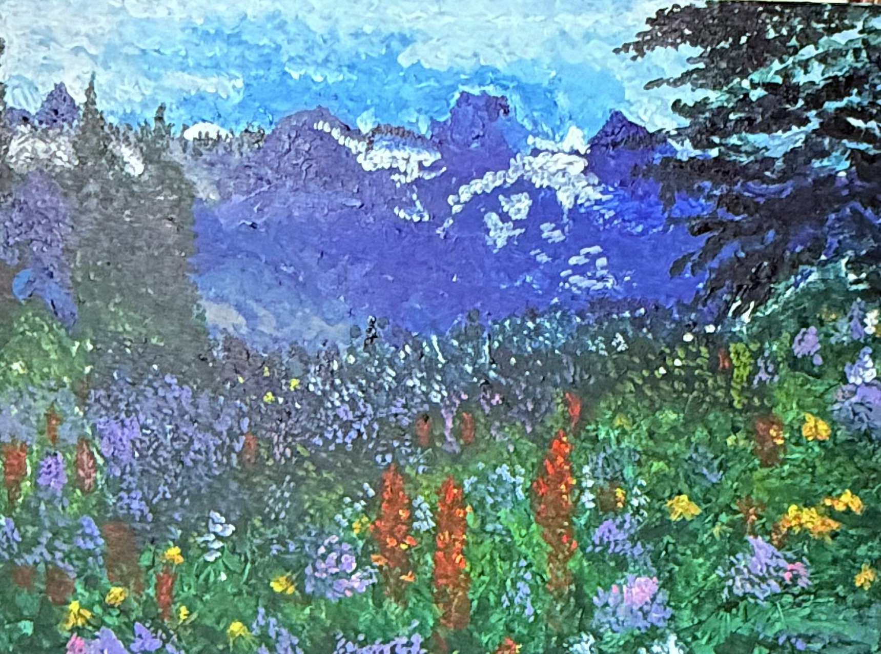 A meadow with flowers near the mountains and trees